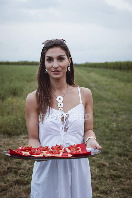 Giovane donna che serve bruschette su un vassoio a un picnic in natura — Foto stock