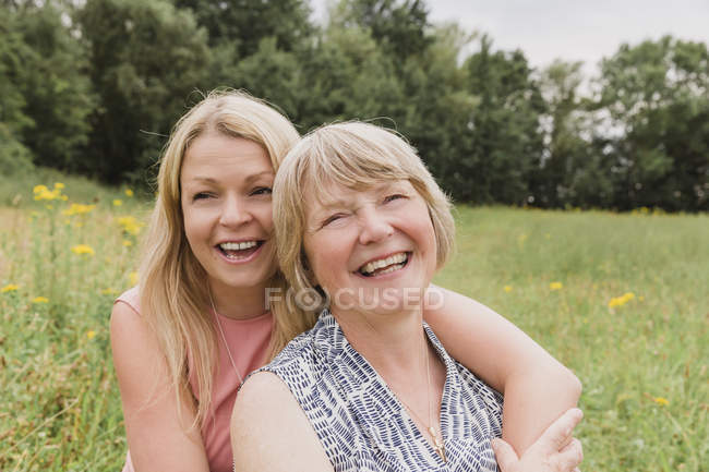 Retrato de madre e hija adulta divirtiéndose en un prado - foto de stock