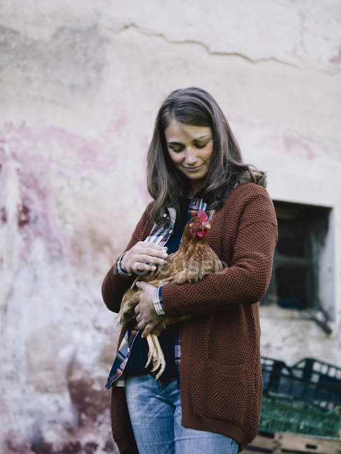 Donna sorridente che tiene il pollo in campagna — Foto stock