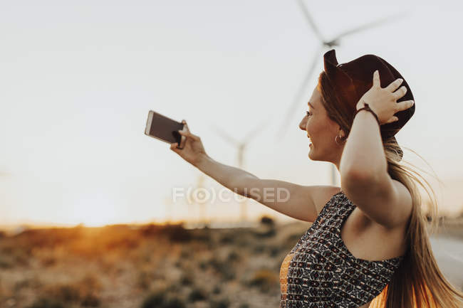Молодая женщина делает селфи на закате в поле — стоковое фото