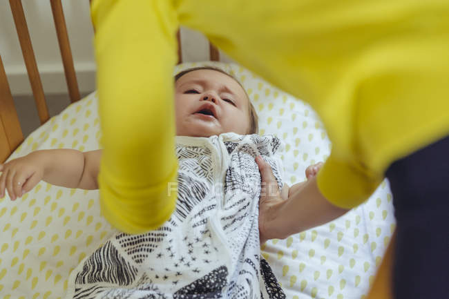 Mother picking up her baby girl from bed — Stock Photo