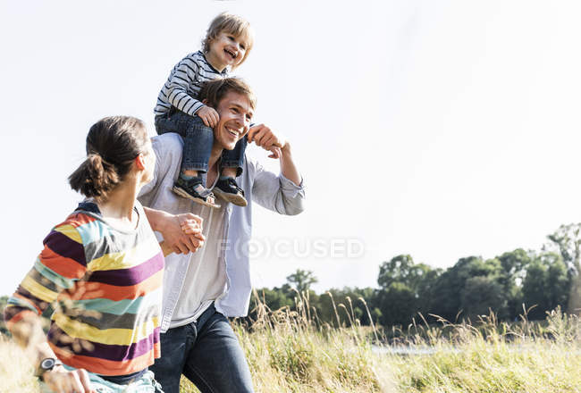 Felice famiglia passeggiando sul lungofiume nella soleggiata giornata estiva — Foto stock