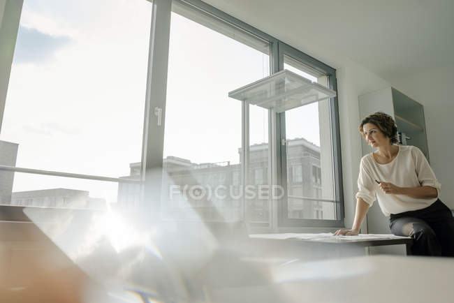 Imprenditrice che lavora in ufficio, seduta sulla scrivania alla finestra — Foto stock