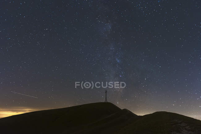 Italy, Marche, silhouette of summit cross on Monte Catria at night — Stock Photo