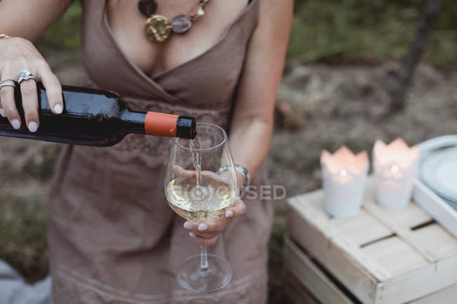 Donna versando vino in vetro su un picnic in natura — Foto stock
