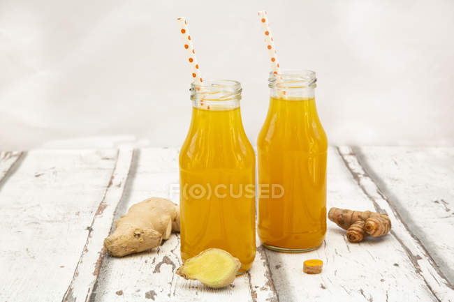 Ginger shot con arancia e curcuma su legno bianco — Foto stock