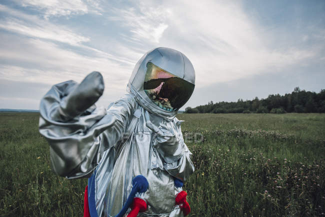 Spaceman dando el dedo en el campo verde - foto de stock