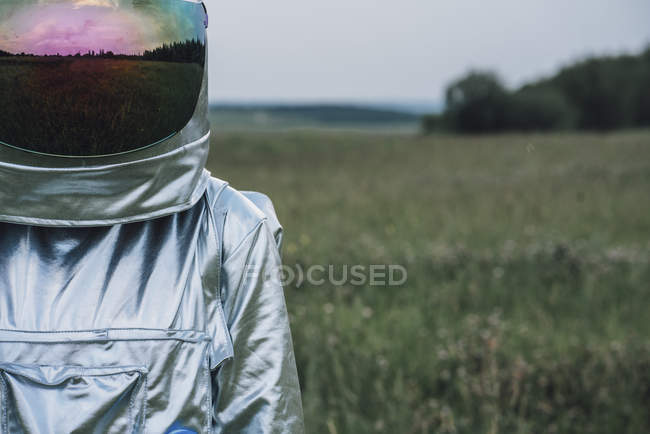 Spaceman standing in nature nature, meadow reflecting in space hat — Stock Photo