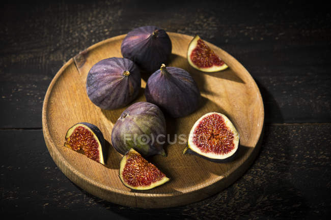 Figs on wooden plate, dark wood — Stock Photo