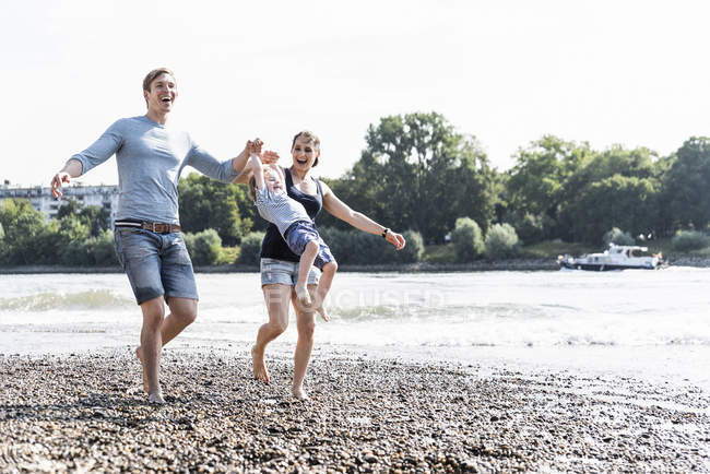 Glückliche Familie spaziert an einem Sommertag am Flussufer — Stockfoto