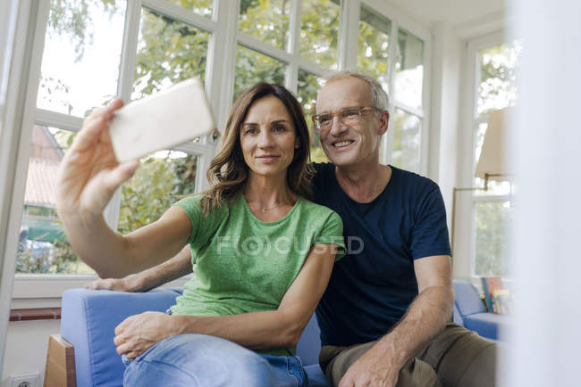 Sorridente coppia matura prendendo selfie a casa — Foto stock