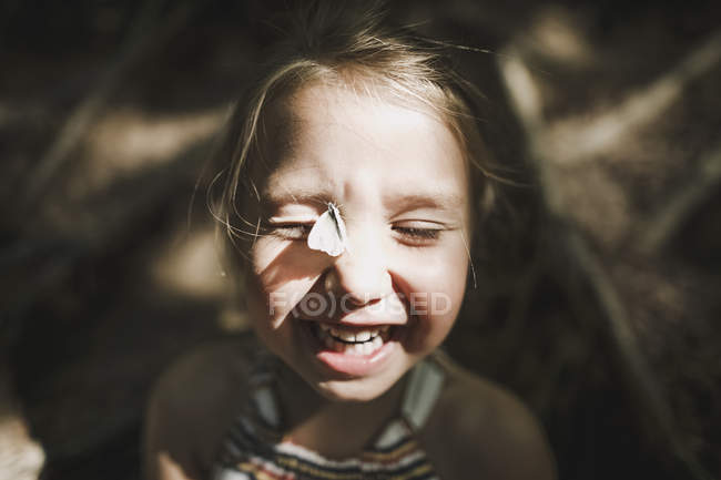 Ritratto di bambina ridente con farfalla sul viso — Foto stock