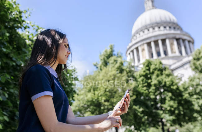 Uk, london, junge frau mit ihrem smartphone in der nähe der kathedrale von st. paul — Stockfoto