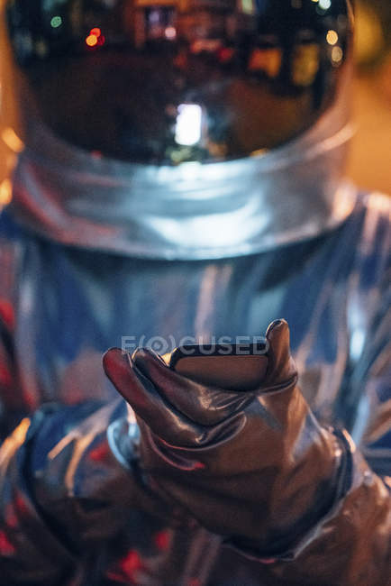 Close-up of spaceman outdoors at night using smartphone — Stock Photo