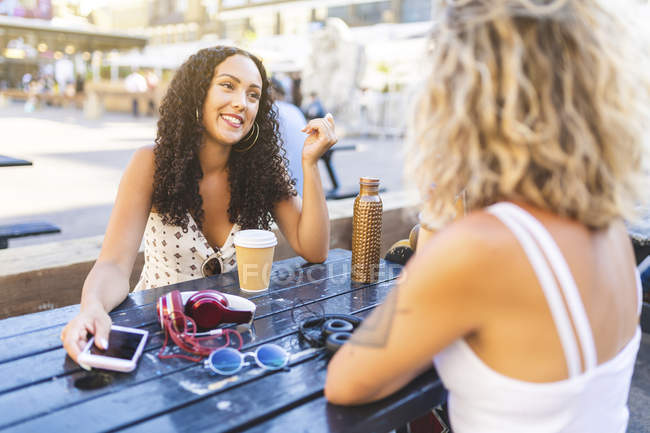 Felices amigas hablando juntas en la mesa al aire libre - foto de stock
