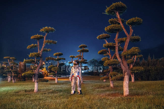 Spaceman standing in illuminated park at night — Stock Photo