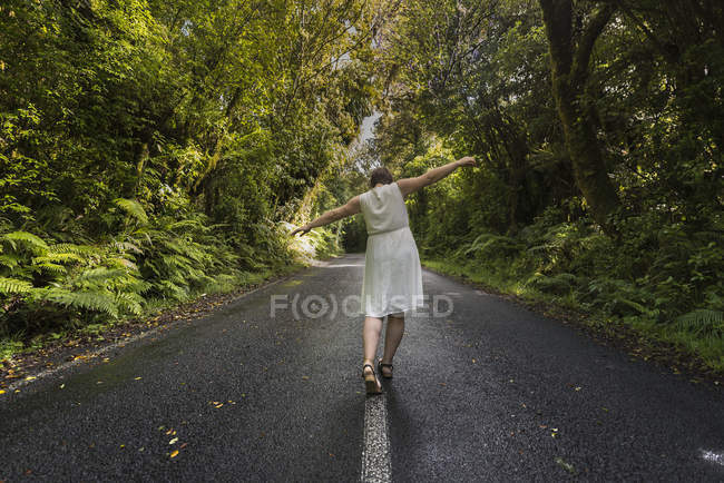 Nova Zelândia, North Island, Egmont National Park, Mulher balanceando na linha central na estrada — Fotografia de Stock