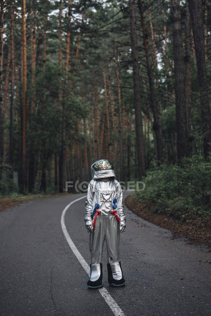Spaceman explorando la naturaleza, de pie en la carretera en el bosque - foto de stock