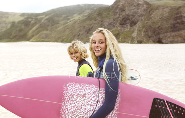 Portrait of two smiling young surfers walking on beach — Stock Photo