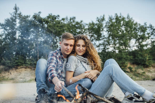 Romantic couple sitting at campfire in nature — happiness, caucasian -  Stock Photo | #270483350