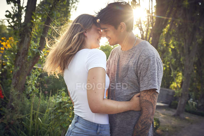 Feliz joven pareja abrazándose y besándose en un parque en verano - foto de stock