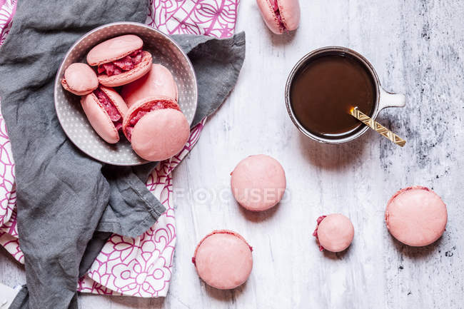 Rosa Macarons gefüllt mit Himbeer-Buttercreme und einer Tasse Kaffee — Stockfoto