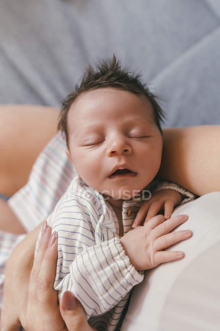 Retrato del bebé recién nacido con los ojos cerrados sostenidos por la madre - foto de stock