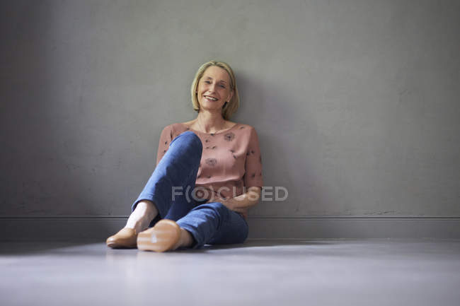 Ritratto di donna matura sorridente a casa seduta sul pavimento — Foto stock