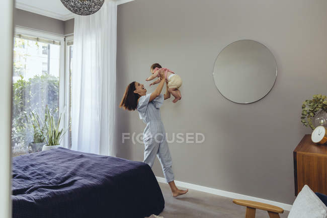 Feliz madre levantando a su bebé en casa - foto de stock