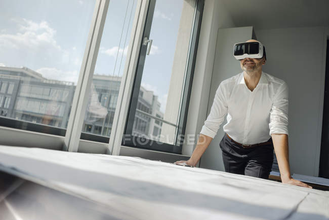 Empresário de pé em seu escritório, usando óculos VR — Fotografia de Stock