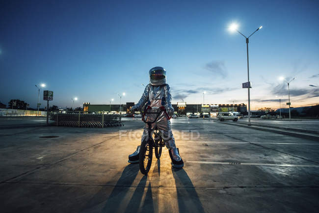 Raumfahrer nachts mit BMX-Rad in der Stadt auf Parkplatz — Stockfoto