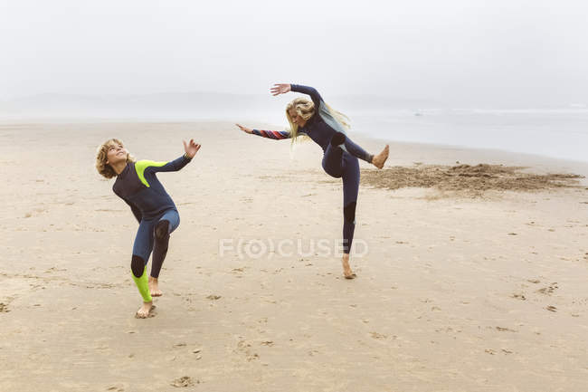 Two young surfers warming up before surfing on beach — Stock Photo