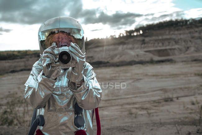 Spaceman on nameless planet taking picture with camera — Stock Photo