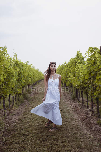 Woman wearing white summer dress, dancing in vineyard — Stock Photo