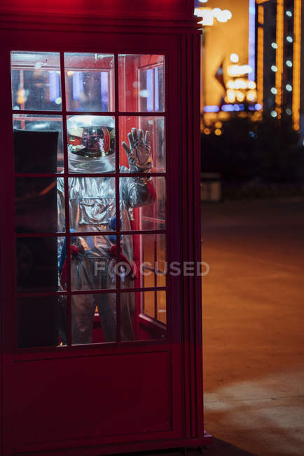 Spaceman standing in telephone box at night — Stock Photo
