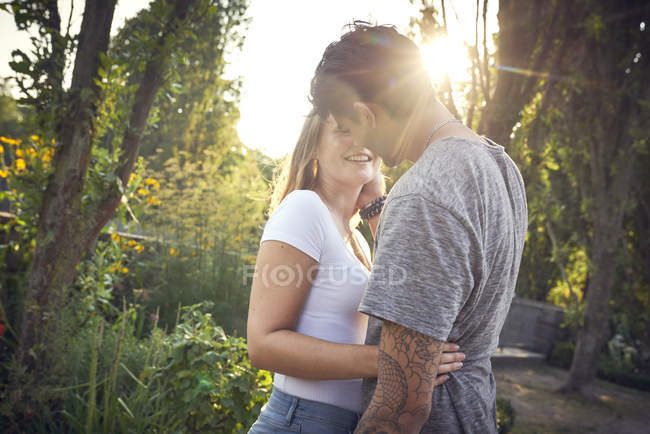Feliz joven pareja abrazándose y besándose en un parque en verano - foto de stock