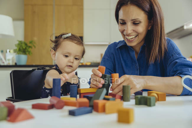 Felice madre e figlia bambino giocare con i blocchi di costruzione — Foto stock