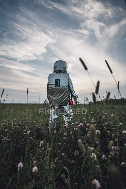 Spaceman exploring nature, standing in blooming meadow — Stock Photo