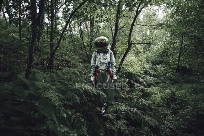 Spaceman explorando la naturaleza, caminando en el bosque verde - foto de stock