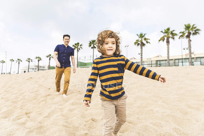 Испания, Барселона, отец и сын гуляют по пляжу — стоковое фото