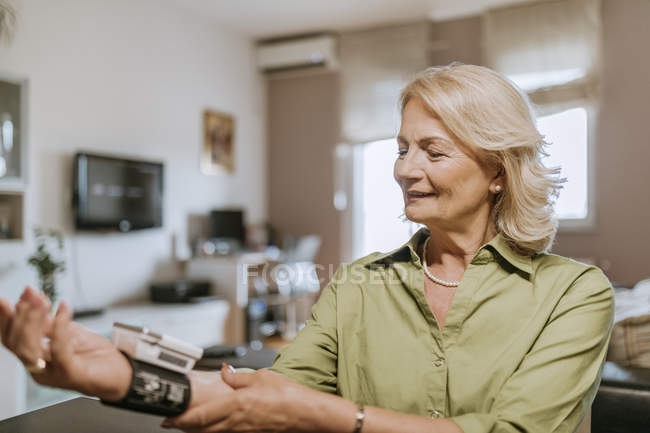 Усміхнена старша жінка приймає кров'яний тиск — стокове фото
