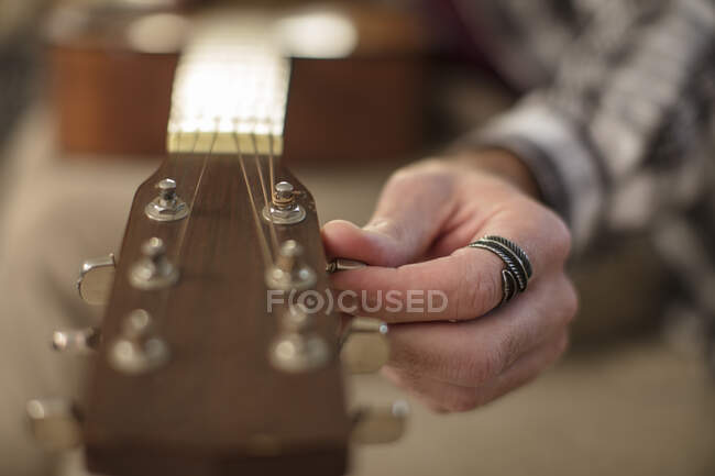 Primer plano de la mano del hombre afinando la guitarra - foto de stock