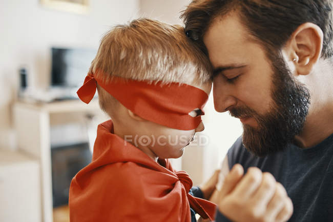 Маленький хлопчик одягнений як супергерой головою до голови зі своїм батьком — стокове фото