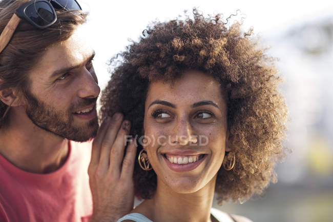 Felice giovane coppia, uomo sussurrando nell'orecchio della donna — Foto stock