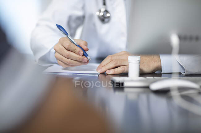 Доктор сидит за своим столом и записывает. — стоковое фото