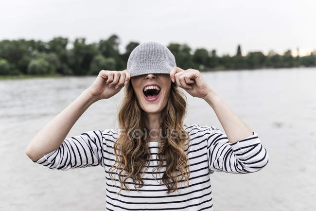 Смеющаяся женщина, играющая с вули-шапкой на реке — стоковое фото