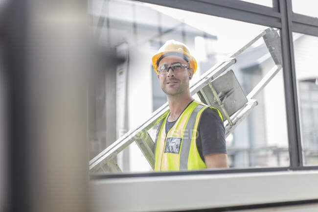 Trabajador de la construcción que lleva la escalera — Stock Photo