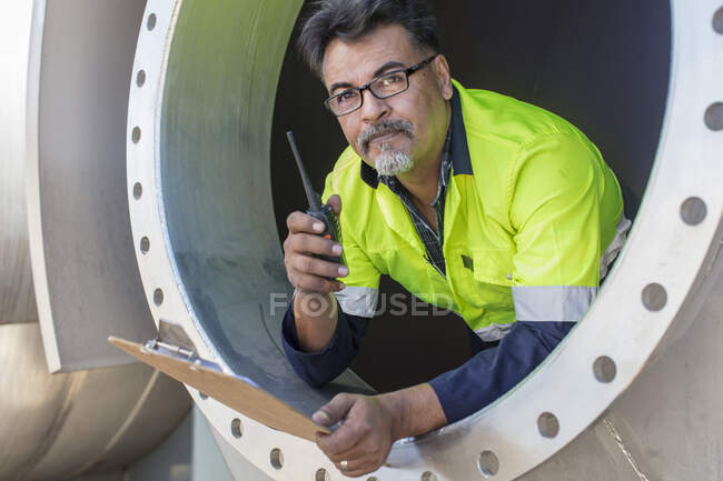 Trabajador en un tanque usando walkie talkie - foto de stock