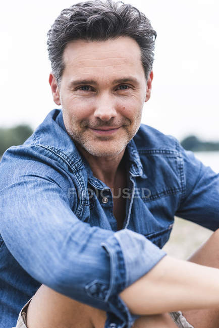 Portrait of smiling man sitting outdoors — Stock Photo