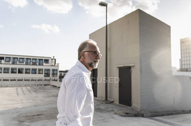 Uomo maturo in piedi sul tetto di un grattacielo — Foto stock